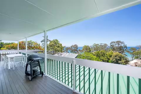 Covered balcony has outdoor dining, a BBQ and fresh air above leafy Little Cove.