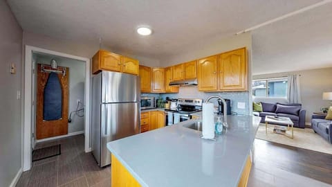 Bright and inviting kitchen with wooden cabinetry, stainless steel appliances, and a modern backsplash, seamlessly flowing into the dining area.