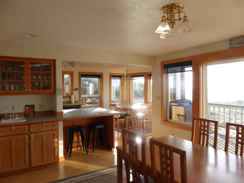 View from dining area with wet bar into bright, ocean view kitchen dining.