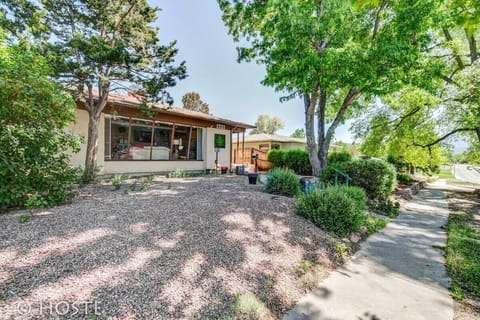 Leafy front yard with gravel landscaping and big shade trees—enjoy a calm arrival with the home’s wide front windows welcoming you in.