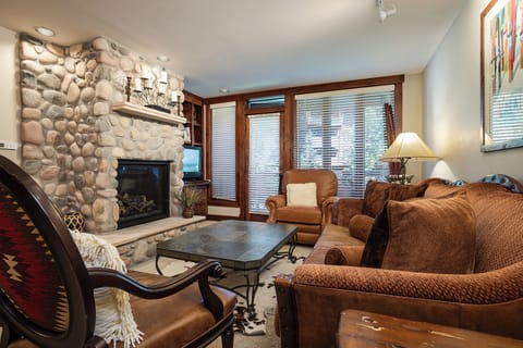 Unwind in your cozy living room with stone fireplace, plush seating, and warm mountain ambiance perfect for relaxing evenings.