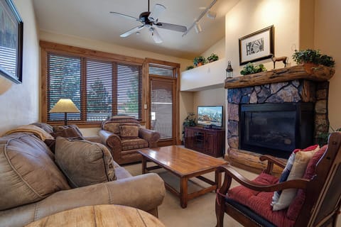 Relax in this cozy living room with rustic stone fireplace, comfortable seating, and warm wood accents.