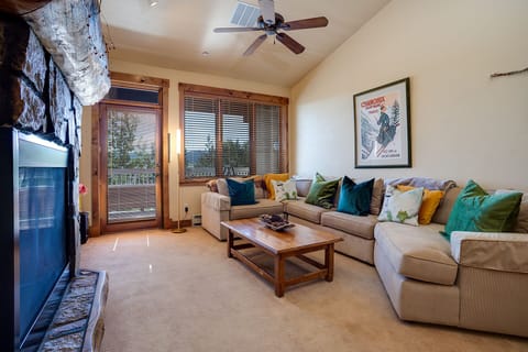 Sink into your spacious sectional with vibrant pillows, while the stone fireplace creates a cozy ambiance for your mountain retreat.