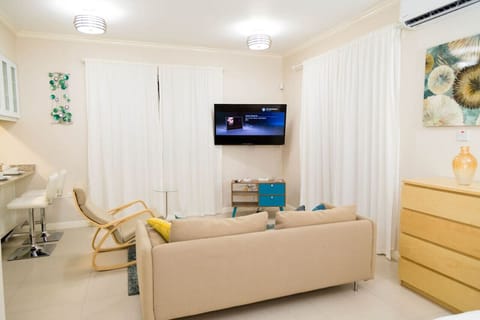 Relax on the cozy sofa & stream your favorites on the wall-mounted TV in this bright living area w/ soft curtains & warm lighting.