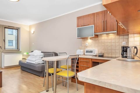 A spacious kitchen with light wooden cabinets, tiled backsplash, and modern appliances including a microwave and stovetop. A small dining area is situated near the entrance, providing a casual spot for meals.