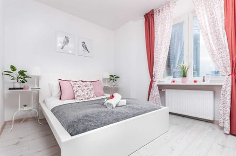 Bright and cozy bedroom with a double bed with gray and yellow and decorative pillows that match the color of the curtains hanging in the window.