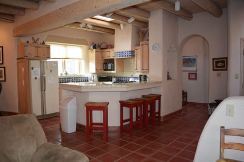 View to open kitchen with bar stools for added dining and view to arched hall to master bedroom