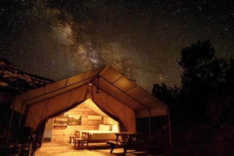 Stargazing from your spacious glamping tent with covered outdoor living space, cozy beds, dining area, and everything you need for a comfortable Southern Utah stay.