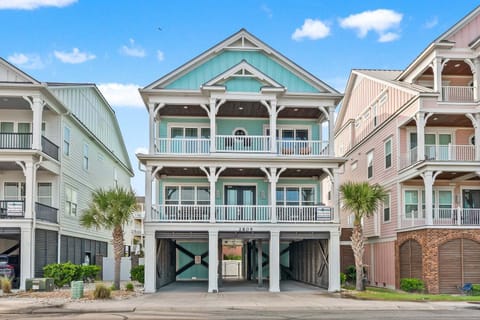 Three-story beach house with balconies and palms at Ocean Current, a 6-bedroom rental from Thomas Beach Vacations