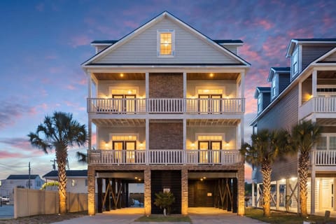 Palm-lined three-story beach house with white railings at A Perfect Escape, a 6-bedroom Cherry Grove vacation rental