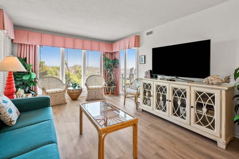 Living room with a teal sofa and wide windows at Surf Villas II C1, a 3-bedroom rental from Thomas Beach Vacations