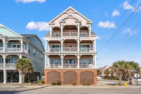 Pink beach house with covered porches at A New Beginning, a 7-bedroom Cherry Grove vacation rental in North Myrtle Beach