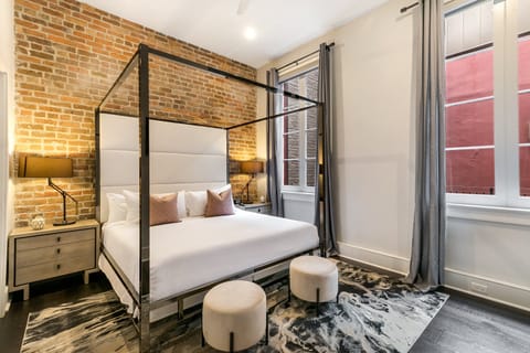 Spacious master bedroom with a king-size bed, ensuite bathroom, and designer built-in closets. Features nightstands, lamps, hangers, luggage rack. white noise machine, and a 43" Samsung Smart 4K TV with streaming and DIRECTV Entertainment.
