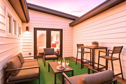 Private rooftop terrace with outdoor seating, dining table, and string lights at sunset