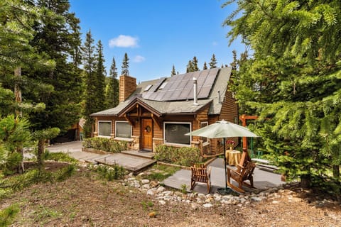 Charming log cabin nestled among towering pines with a welcoming patio where you can sip your morning coffee surrounded by nature's serenity and mountain air.