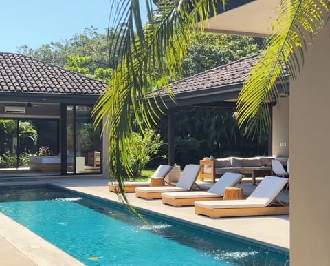 Resort style pool surrounded by lush vegetation, bedrooms & outdoor lounge area 