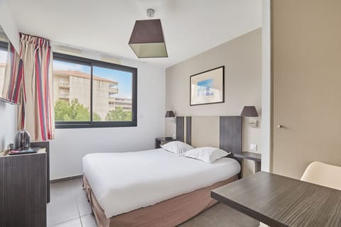 This cozy studio features a modern bed, ample natural light from large windows, and stylish decor, perfect for a comfortable stay in Marseille.