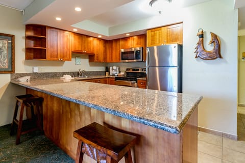 Your fully equipped kitchen features rich wood cabinetry, granite countertops, and modern stainless steel appliances. Gather around the breakfast bar to plan your island adventures or prepare meals together in this inviting space.