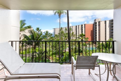 Step onto your private balcony to unwind on the sun lounger, enjoy meals at your outdoor table, and take in tropical garden and pool views framed by swaying palms and neighboring buildings.