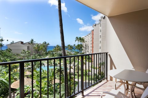 Balcony overlooking tropical grounds with pool, swaying palms, and ocean views—a serene spot to sip morning coffee or watch the sunset unfold.