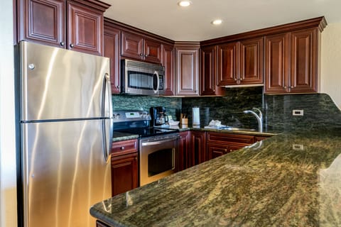Step into your fully equipped kitchen, featuring rich wood cabinetry, gleaming granite countertops, and stainless steel appliances ready for preparing your favorite meals during your stay.