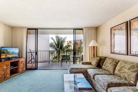 Step into your tropical living space where island-patterned furnishings welcome you home, and your private balcony frames swaying palms and distant mountain views, inviting you to unwind in paradise.