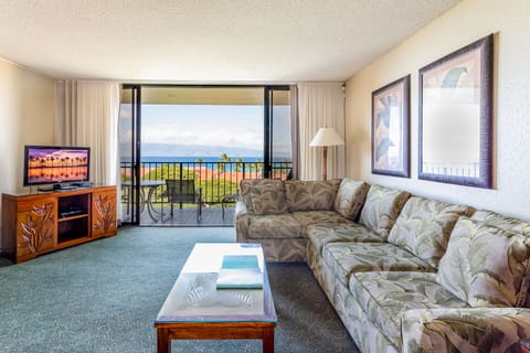 Unwind in your spacious living room where tropical-print furnishings and floor-to-ceiling windows frame breathtaking ocean views—your perfect island escape awaits.