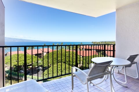 Private balcony overlooking coastal resort grounds and the Pacific Ocean, with comfortable seating for enjoying panoramic island and mountain views during your Hawaiian getaway.