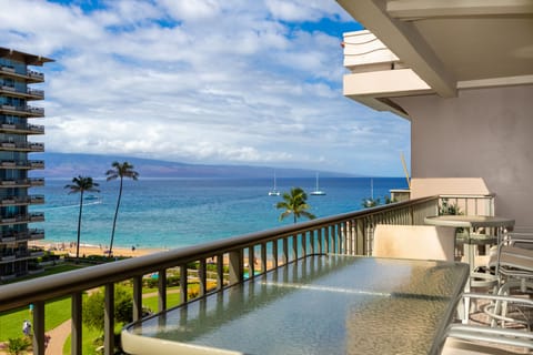 A stunning oceanfront balcony showcasing turquoise waters, palm trees, white sailboats, and sweeping island views—your private retreat to soak in paradise and ocean breezes.