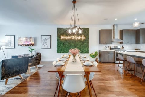 Dining table, neon sign, and kitchen island create an open floor plan that flows for group meals, game night snacks, and pre-night-out hangs