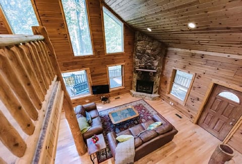 Two leather sofas face a stone fireplace in the wood-paneled living room with large triangular windows.
