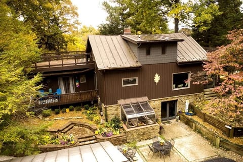 Exterior view of the multi-level house with brown siding, stone foundation, balconies, and surrounding autumn foliage.