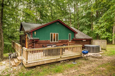 Outdoor deck with wooden railing, seating area, charcoal grill, and hot tub at Sunset Getaway cabin in Indiana.