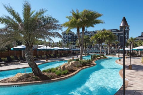  Winding resort pool with tropical landscaping, perfect for leisurely swims.