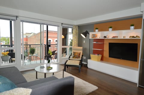 Bright, open-concept main living area with wall-mounted Smart TV and direct sliding glass door access to the private balcony.