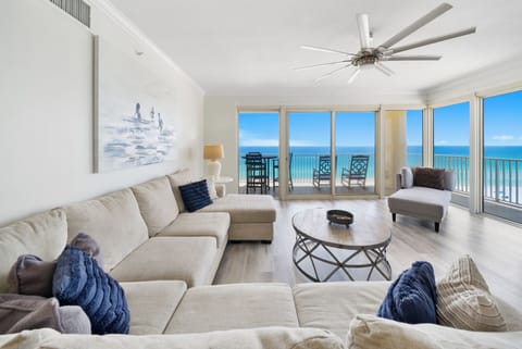 Sink into plush seating while ocean waves fill your view through floor-to-ceiling windows in this bright, coastal living space.