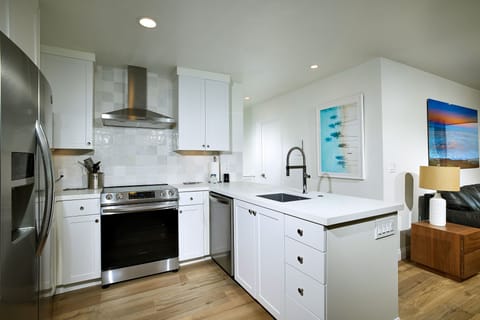The remodeled kitchen is equipped with dishes, pots and pans, and serving utensils.