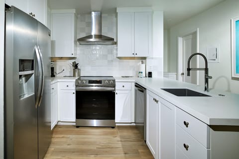 The kitchen features quartz counter tops, stainless appliances, and designer tile backsplash.