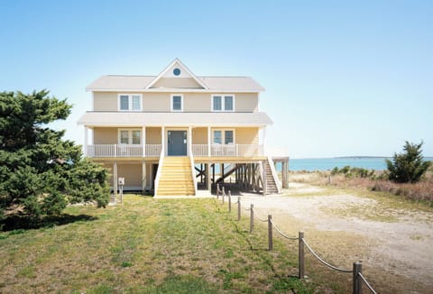 Elevated coastal home on stilts with ocean access, surrounded by natural dunes and maritime vegetation, offering beachfront proximity and scenic waterfront positioning.