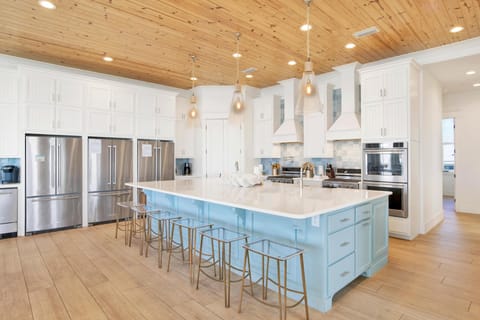 Kitchen has 3 full sized refrigerators.