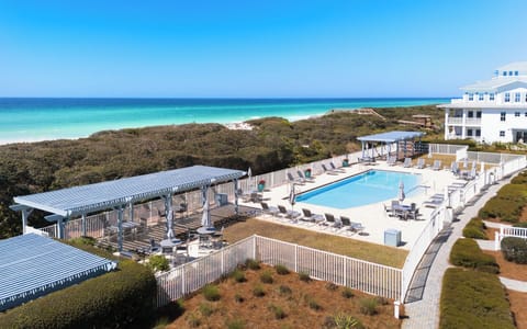 Beachfront property featuring elevated pool deck with pristine white sand beach and turquoise waters beyond natural dune vegetation.