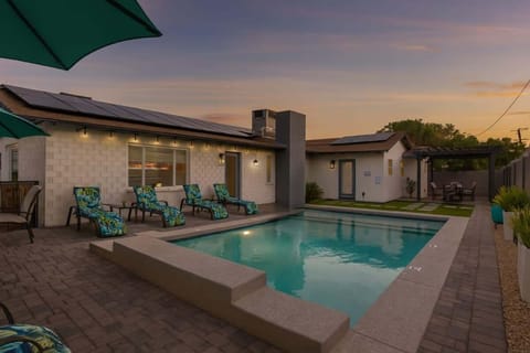 Stunning valley backyard featuring a sparkling blue heated pool with sun loungers, a BBQ grill, and outdoor dining while bistro lights set the mood.