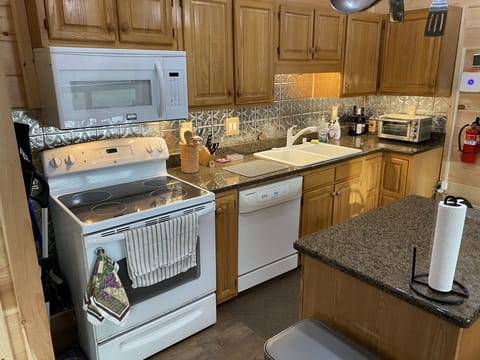 Complete kitchen including granite counters with pot rack over island.