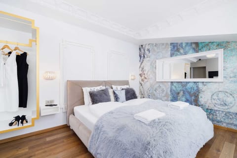 A cozy bedroom with a double bed, soft bedding, and a decorative wallpaper accent wall.