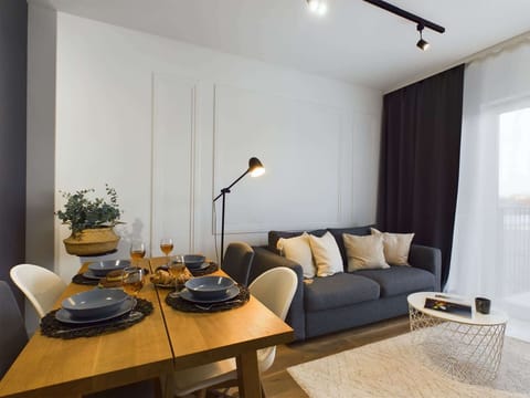 A cozy living room featuring a beige sofa, a round coffee table, and a stylish rug, creating a comfortable and modern space.