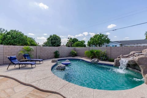 Stunning backyard retreat featuring a private pool with a waterfall, sun loungers, BBQ grill, outdoor seating, Smart TV, and an outdoor dining area.