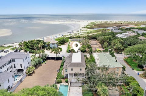 Aerial view of coastal properties nestled among lush greenery, with sweeping beach and ocean vistas stretching across the horizon, offering a serene beachside setting.