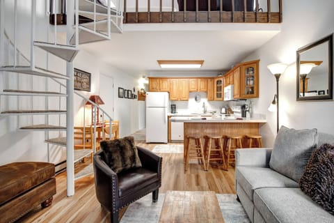 Relax in your spacious open-concept living area featuring a fully equipped kitchen, comfortable seating, and charming spiral staircase to the loft above.