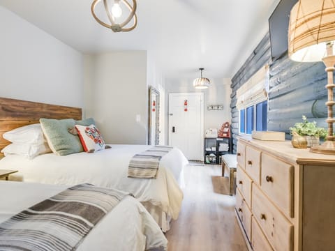 The Nature Suite at Cabins on the Square — two queen beds with premium Comphy linens, the highest-rated of the three creekside suites in downtown Wimberley.