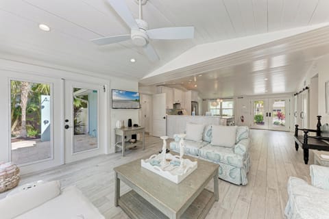 Step into your bright coastal haven with soaring ceilings, comfortable seating, and seamless indoor-outdoor flow through glass doors.
